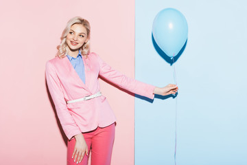 smiling woman holding balloon on pink and blue background