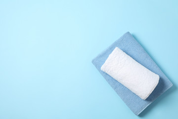Folded color towels on blue background, space for text