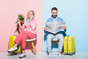 Plakat attractive woman talking on smartphone and smiling man reading newspaper on pink and blue background