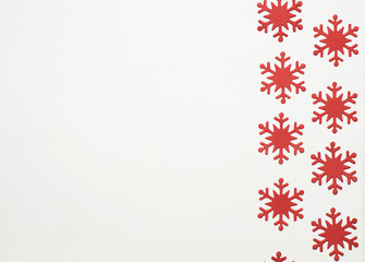 Fototapeta na wymiar Many red snowflakes lie flat on a white background
