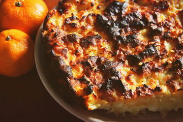 Homemade pie and tangerines on a wooden background