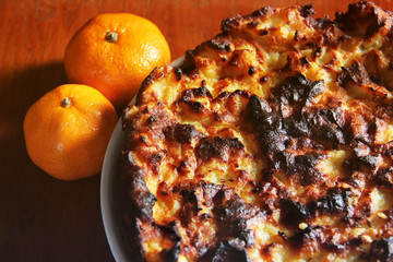 Homemade pie and tangerines on a wooden background