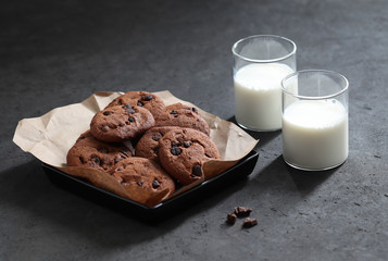 Chocolate chip cookies with dark chocolate slices with milk and coffee on a dark gray background