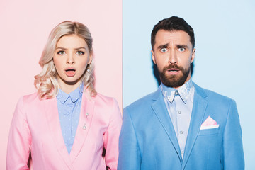 shocked woman and handsome man looking at camera on pink and blue background