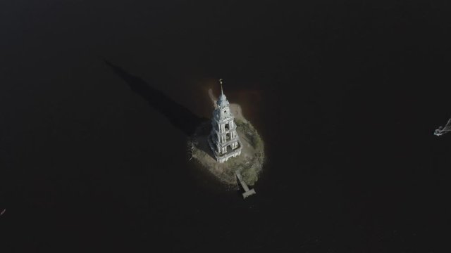 Aerial footage of flooded Kalyazin Bell Tower in Uglich Reservoir on the Volga River. Boat sailing to the tower. Kalyazin, Russia. Kalyazin from drone.