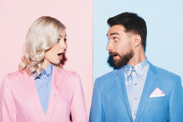 shocked woman and handsome man looking at each other on pink and blue background