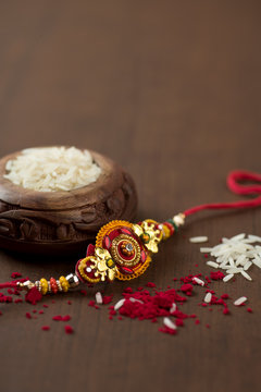 Indian festival: Raksha Bandhan background with an elegant Rakhi, Rice Grains and Kumkum. A traditional Indian wrist band which is a symbol of love between Brothers and Sisters.
