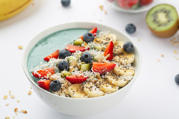 Detox breakfast smoothie bowl with spirulina, blueberry, strawberry, granola, kiwi, banana, coconut and chia seeds. Spirulina smoothie with berries and fruits in bowl.  