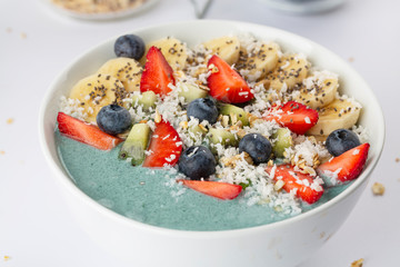 Detox breakfast smoothie bowl with spirulina, blueberry, strawberry, granola, kiwi, banana, coconut and chia seeds. Spirulina smoothie with berries and fruits in bowl.  