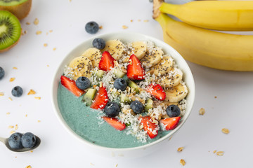 Detox breakfast smoothie bowl with spirulina, blueberry, strawberry, granola, kiwi, banana, coconut and chia seeds. Spirulina smoothie with berries and fruits in bowl.  