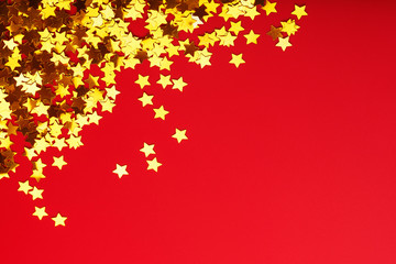 Gold stars on red background. The concept of greeting cards, headlines and web site. A scattering of Golden stars