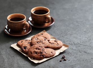 Chocolate chip cookies with dark chocolate slices with milk and coffee on a dark gray background