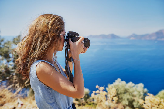 Beautiful woman professional photographer with dslr camera shooting landscape in sunset light in Turkey