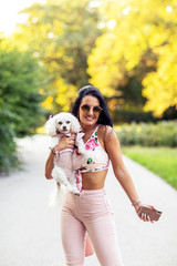 Fashion girl in park in pink with her small dog on her hand