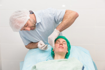 Obraz premium Cosmetologist applying cream on female face in cosmetology salon.