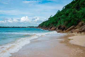 A beautiful sandy tropical beach with stone cliffs and a jungle above them. Jungle Beach, Unawatuna, Sri Lanka. A popular tourist destination is a tropical beach and a paradise vacation spot