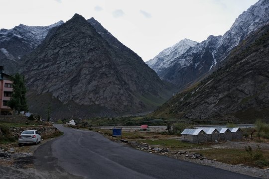 Gray dramatic morning empty road in the village between the mountains. 