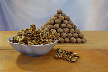 A bowl with walnut kernels and a lot of walnuts folded in the form of a pyramid .