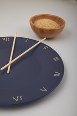 clock, time concept with rice on a blue plate, top view