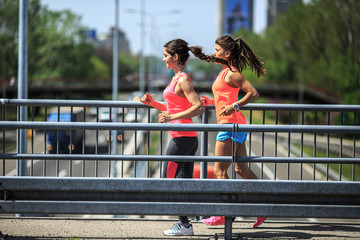 Two female runners jogging around the city.Urban workout concept.	