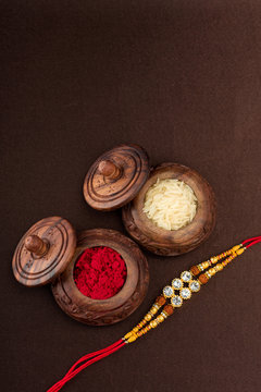 Raksha Bandhan background with an elegant Rakhi, Rice Grains and Kumkum. A traditional Indian wrist band which is a symbol of love between Brothers and Sisters.