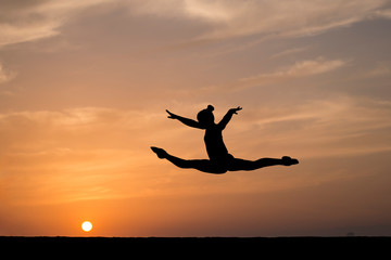 Fototapeta na wymiar silhouette of female gymnast on balance beam in sunset