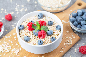 Healthy breakfast - oatmeal with fresh berries in a bowl. Oatmeal porridge with blueberries, raspberries and mint.