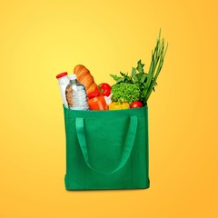 Bag full of groceries on wooden desk with pastel background
