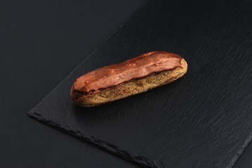 eclair with custard cream and chocolate chips on black plate