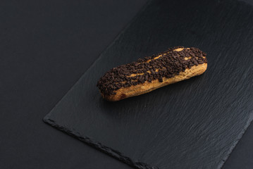 eclair with custard cream and chocolate chips on black plate