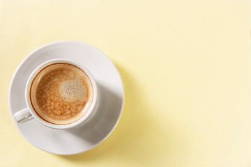 Cup with aromatic coffee in a white cup on a yellow background. Space for text.