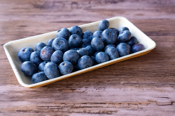 blueberries in a bowl of palm leaves after harvest on a kitchen table