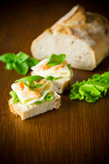 sandwich with cheese, salad leaves and red fish on a wooden