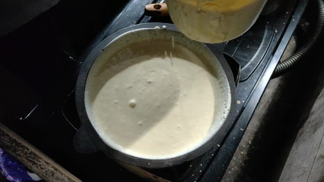 the process of putting the cake mixture into the baking pan, this white cake mixture is runny made of water, eggs, cake developer, flour, salt, sugar etc.