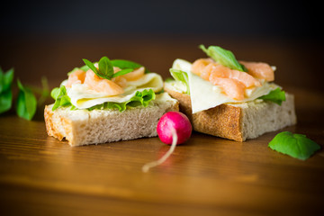 sandwich with cheese, salad leaves and red fish on a wooden
