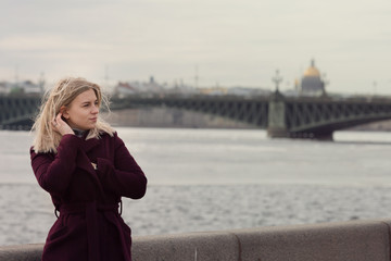 Fototapeta premium Portrait of a blond woman walking on river embankment.Windy hair.