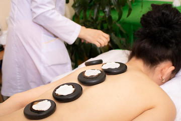 Girl on a stone therapy, hot stone massage. Restorative procedure for body and soul - stone massage