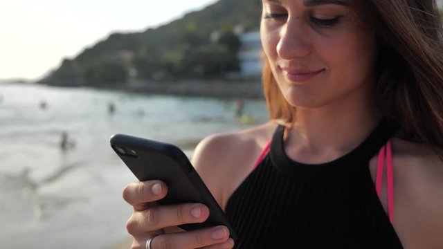 Portrait of a girl on the background of a cottage on the ocean .Exotic landscape. She clicks on the buttons of her smartphone. Vacation concept 4k