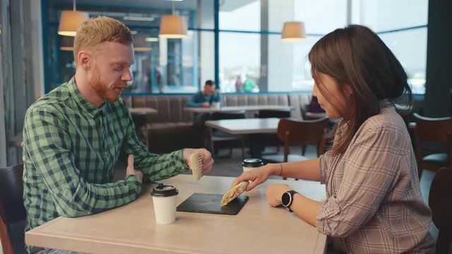 Man and woman couple eating doner kebap kebab chicken vegetable roll in smart cafe. Middle eastern fast food cuisine for students