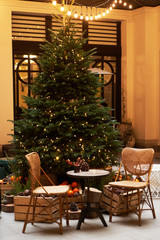 Fototapeta na wymiar Christmas tree with festive table with mandarins, oranges and pine tree cone