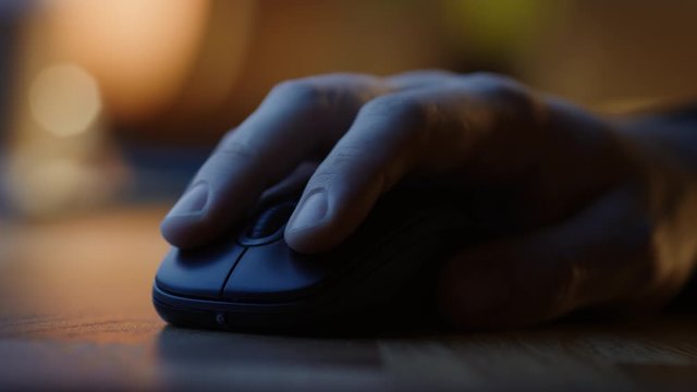 Close-up Macro Shot: Person's Hand Using Wireless Computer Mouse, Scrolls through Apps and Websites with a Wheel and Clicks on Buttons. In the Background Evening Light