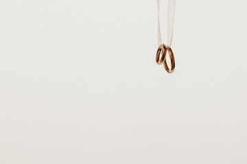 Two golden wedding rings hanging on a ribbon, isolated on white background