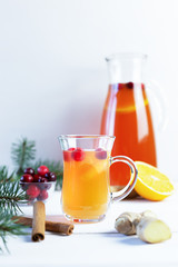 Orange and cranberry punch with orange slices and spices on a white table. Hot drinks for winter and Christmas.