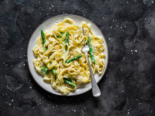 Mascarpone cheese sauce fettuccine pasta with asparagus on a dark background, top view