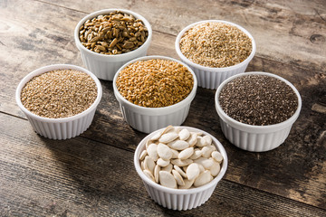 Assortment of different seeds in bowl on wooden table. Pumpkin, linen, chia, sunflower, and sesame seeds	