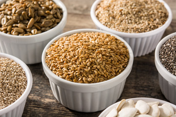 Assortment of different seeds in bowl on wooden table. Pumpkin, linen, chia, sunflower, and sesame seeds	