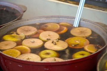 Traditional winter warming alcoholic drink - mulled wine. Hot wine with fruits and spices and ladle in vintage metal bowler on dark gray background. Copy space