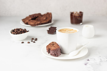 Traditional Italian homemade biscotti cookies or cantuccini with chocolate and a cup of coffee on a light grey background.