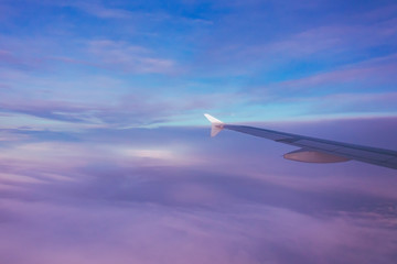 Scenic clouds at sunrise from an airplane, view of the wing.