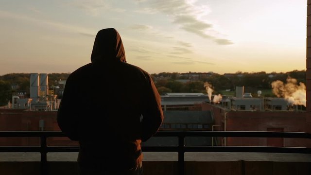 silhouette of man at sunset looking over the city thinking